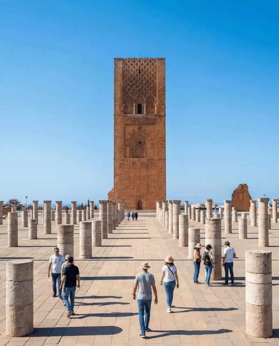 A majestic shot of the Hassan Tower in nearby Rabat, standing tall amidst the grid of ancient, ruined stone columns on the esplanade.