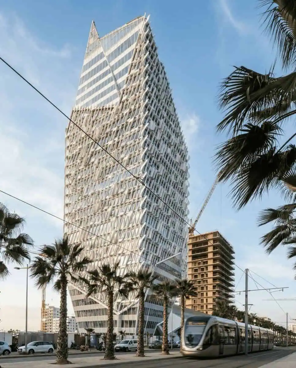 A striking architectural shot of the futuristic, white aerodynamic CFC Tower (Casa Finance City) gleaming against a blue sky in the new Anfa district.