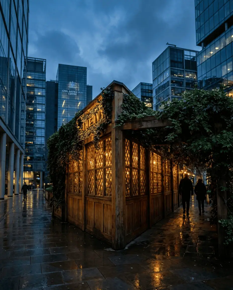 An atmospheric evening shot of The Ivy in Spinningfields, with its timber-framed structure and lush greenery glowing with warm lights amidst modern glass skyscrapers.